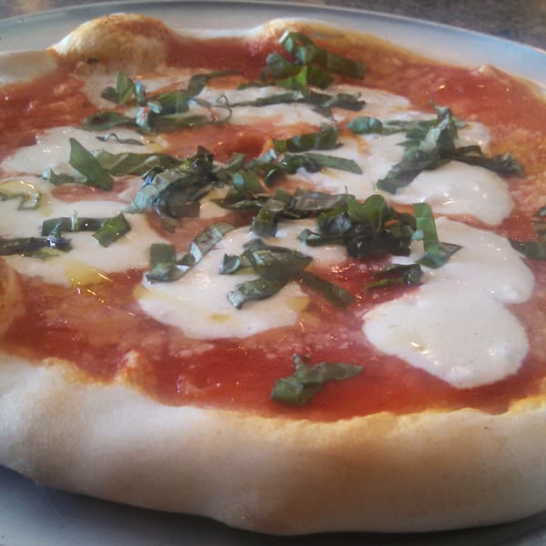A close-up of a freshly baked Margherita pizza with melted mozzarella, red sauce, and basil.
